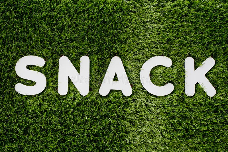 Fassen Sie weißes hölzernes Alphabet des SNACKS auf gree Gras-Hintergrund textur ab lizenzfreies stockbild Fassen Sie weißes hölzernes Alphabet des SNACKS auf gree Gras-Hintergrund textur ab lizenzfreies stockbild