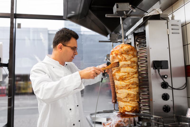 Chef slicing doner meat from spit at kebab shop