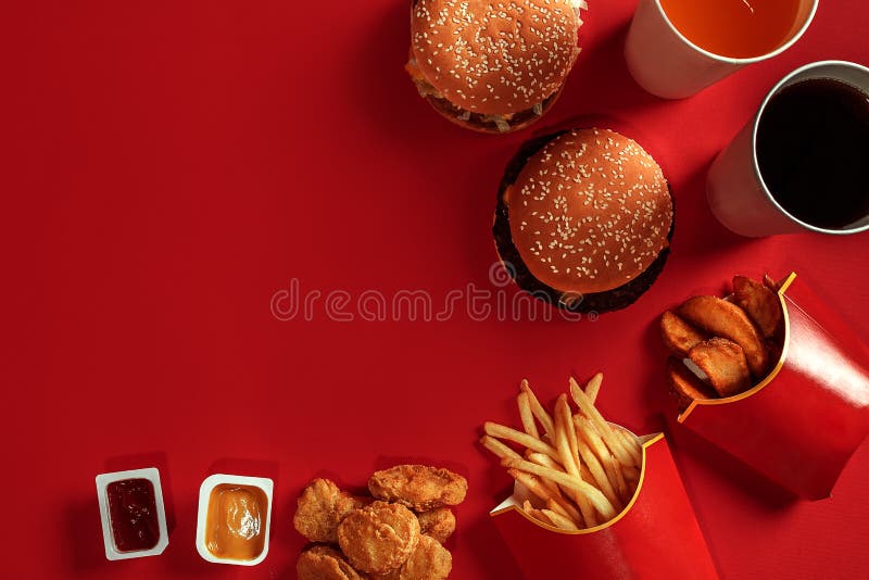 Fast food dish top view. Meat burger, potato chips and glass of drink on red background. Takeaway composition.