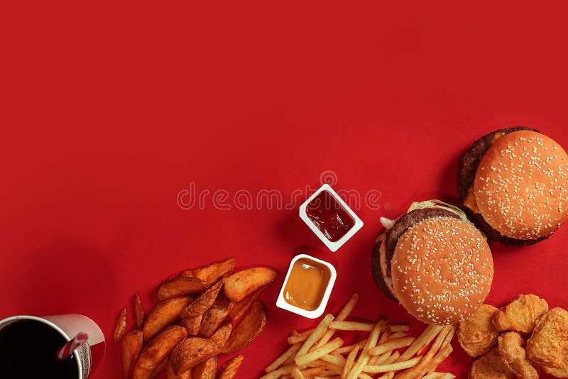 Fast food dish top view. Meat burger, potato chips and glass of drink on red background. Takeaway composition.