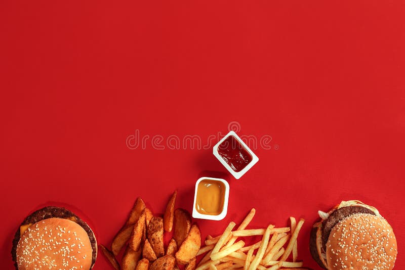 Fast food dish top view. Meat burger, potato chips and nuggets on red background. Takeaway composition. Top view