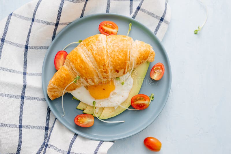 Faszerujący croissant z avocado, omletu jajkiem i świeżym warzywem, obraz stock Faszerujący croissant z avocado, omletu jajkiem i świeżym warzywem, obraz stock