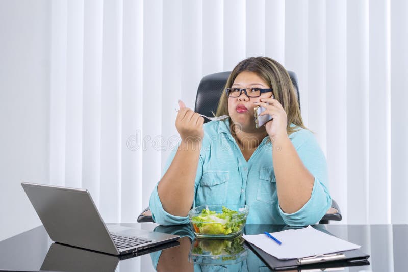 Fat Asian woman eating lettuce salad while calling