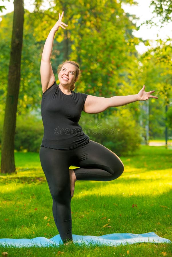 fat cheerful woman doing yoga in the park