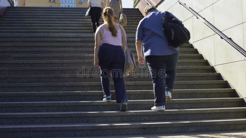 Fat couple walking together on stairs, problems of overweight among young people