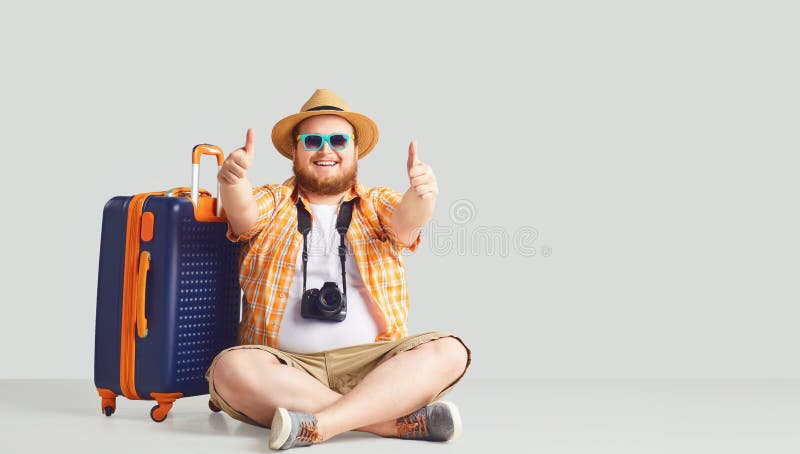 Fat funny man with a suitcase smiling on a gray background.