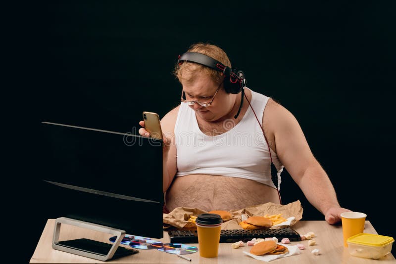 Fat man with big stomach making a phone call while using the computer. 