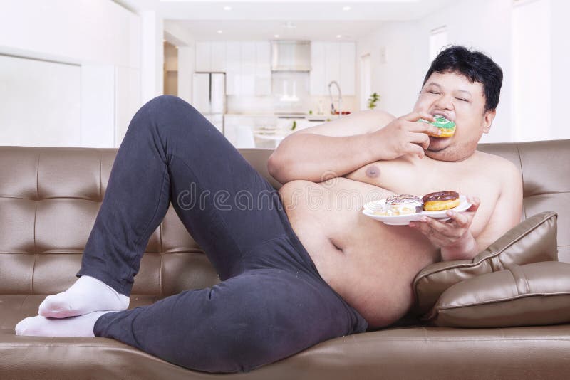 Fat man eats sweet food at home. 