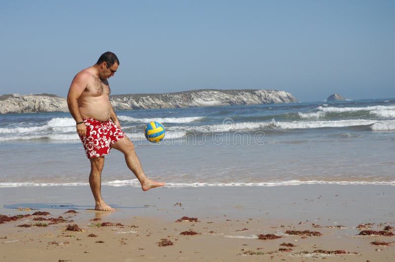 Fat man playing with a ball on the beach