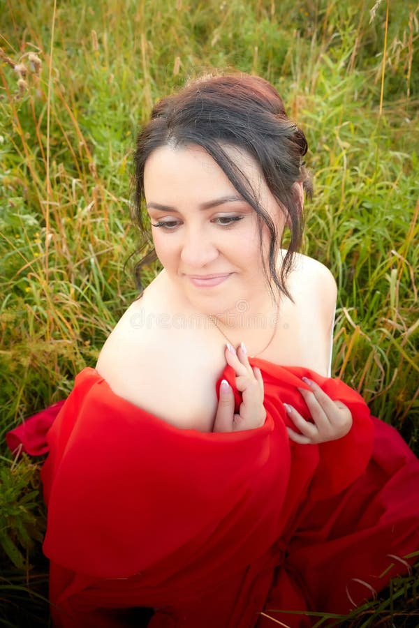 Fat Plump Chubby Pleasant Woman Or Girl In Elegant Red Dres In Green Grass Field Model Posing