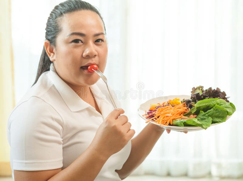 Asian fat woman eating salad on white stock image.