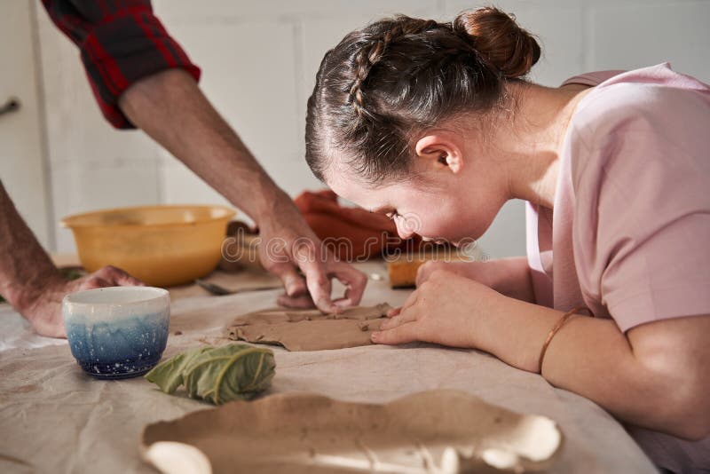 Fata care face cu grijă farfurie din lut sub supravegherea mentorului stock image