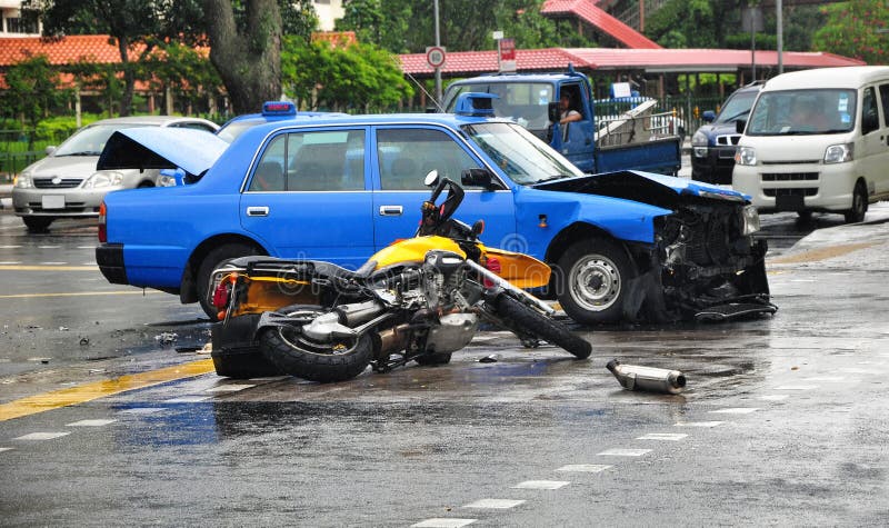 A fatal road accident involving a motorbike and a taxi on a wet and slippery road.