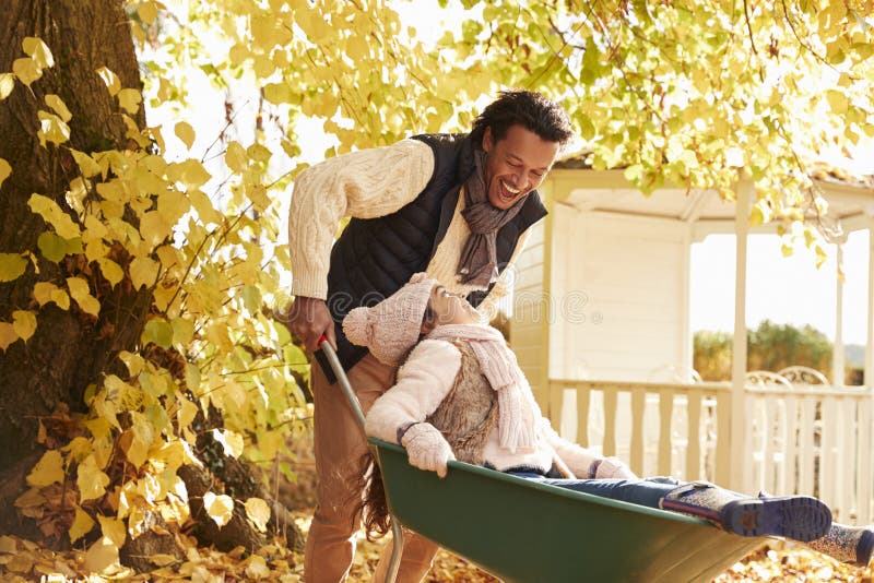 Father In Autumn Garden Gives Daughter Ride In Wheelbarrow stock images Father In Autumn Garden Gives Daughter Ride In Wheelbarrow stock images