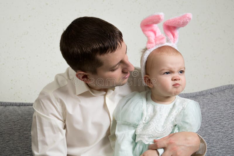 Dad and baby with hare ears, the girl is wrinkling her nose royalty free stock photo Dad and baby with hare ears, the girl is wrinkling her nose royalty free stock photo