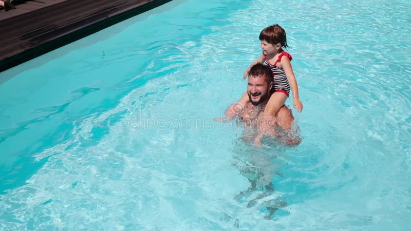 Father carrying daughter on shoulders in swimming pool