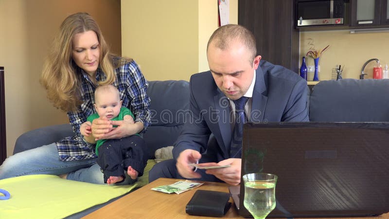 Father count family budget. Mother with baby play on sofa