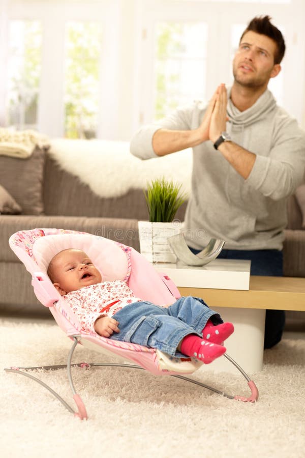 Young father praying for peace by crying baby. Young father praying for peace by crying baby.