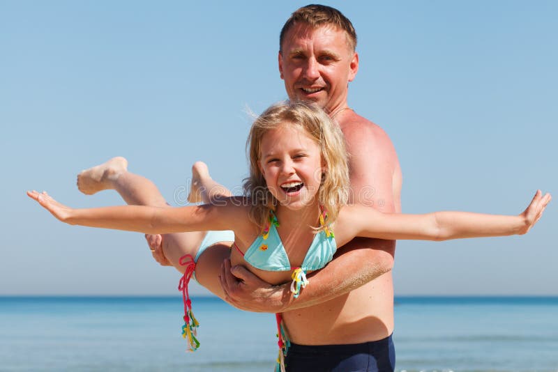 Father and daughter having fun on beach.