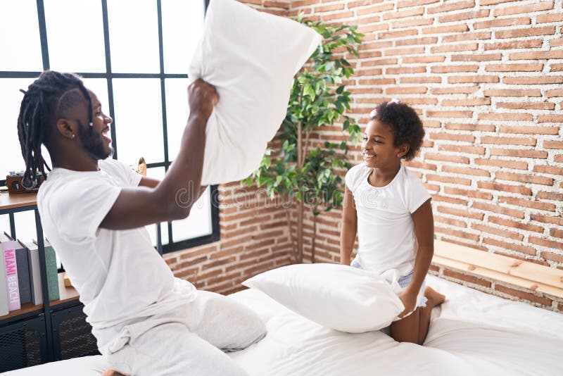Father and Daughter Lying on Bed Fighting with Pillow at Bedroom Stock