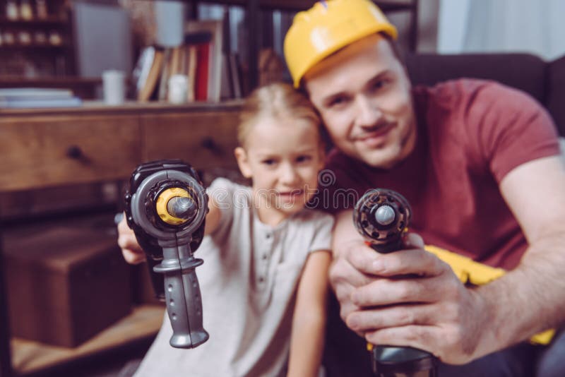 Father and daughter posing with toy drills while making a wooden frame at home royalty free stock photos Father and daughter posing with toy drills while making a wooden frame at home royalty free stock photos