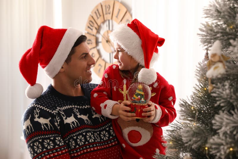 Father and Daughter with Snow Globe Near Christmas Tree at Home Stock