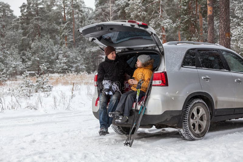Father and daughter talking together after sports activities such as ski and ice skate. Sitting back trunk of suv at winter season