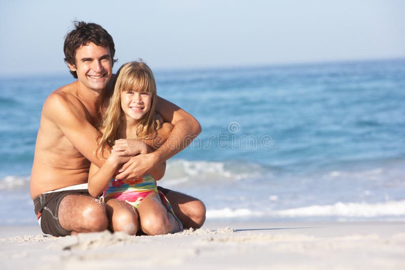 Father And Daughter Wearing Swimwear Sitting Down.