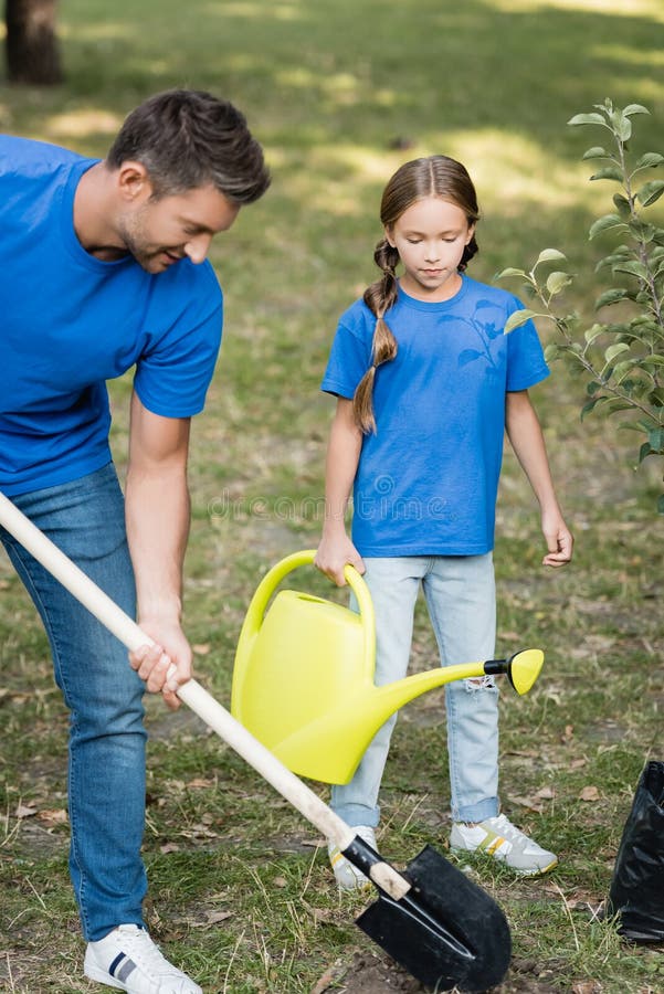 father and son digging ground in forest with shovels, ecology