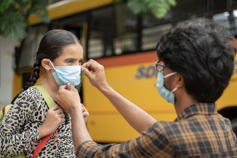 Father helping daughter to wear mask before getting inside the school bus as coronavirus or covid-19 safety measures - concept of royalty free stock photos Father helping daughter to wear mask before getting inside the school bus as coronavirus or covid-19 safety measures - concept of royalty free stock photos
