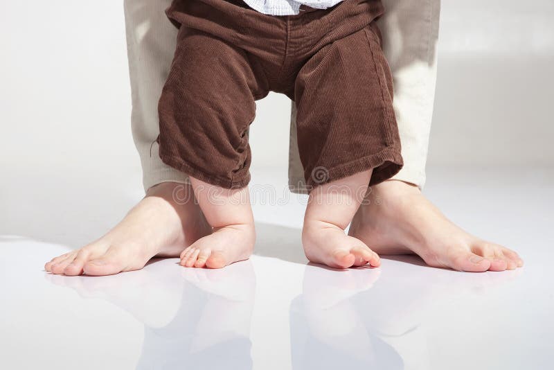 Father is helping her son to make first steps