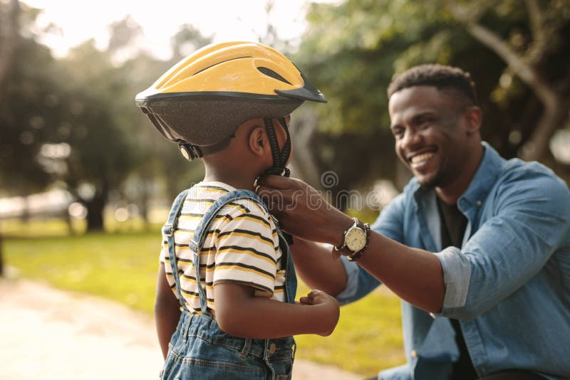 Father helping his son to wear a cycling helmet royalty free stock photo Father helping his son to wear a cycling helmet royalty free stock photo