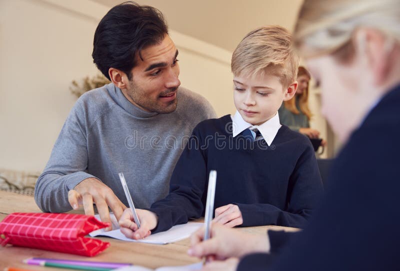 Father Helping Son and Daughter Wearing School Uniform with Homework at