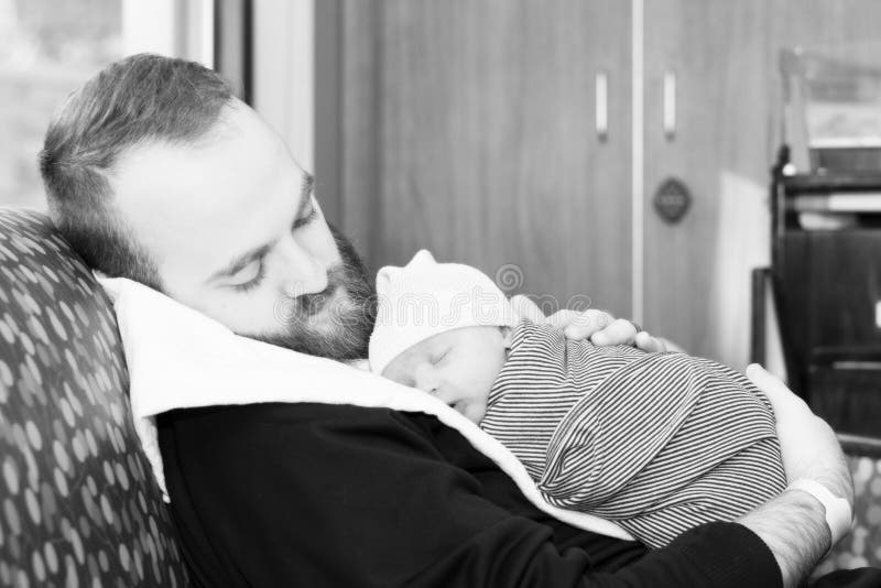 Father Holds Newborn Baby Boy Wrapped in a Blanket as He Sleeps on His Dad`s Chest. Black & White Photo. Father Holds Newborn Baby Boy Wrapped in a Blanket as He