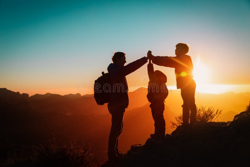 Father with kids travel in sunset mountains, family high five in nature