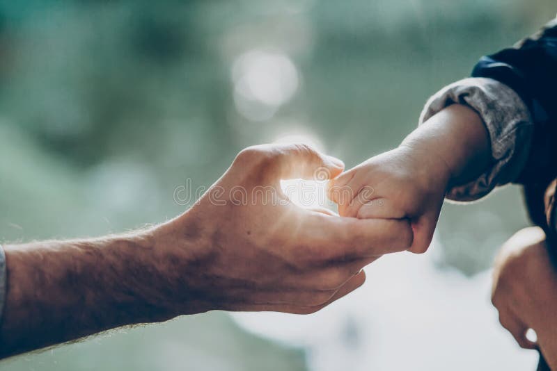 Father and little son holding hands in sunlight. father`s hand lead his child son in summer forest nature outdoor, trust