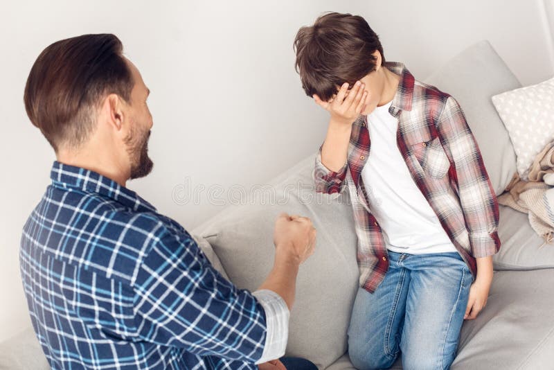 Father and little son at home sitting on sofa playing rock–paper–scissors boy lost stock photo Father and little son at home sitting on sofa playing rock–paper–scissors boy lost stock photo