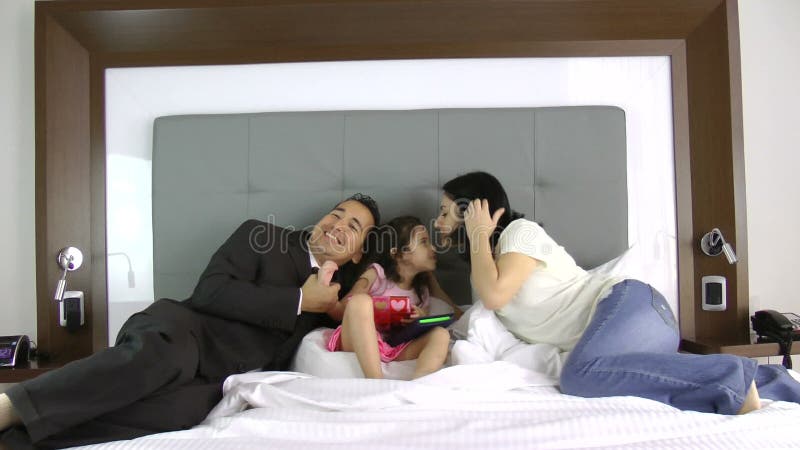 Father and mother giving a gift to his little daughter in the bedroom
