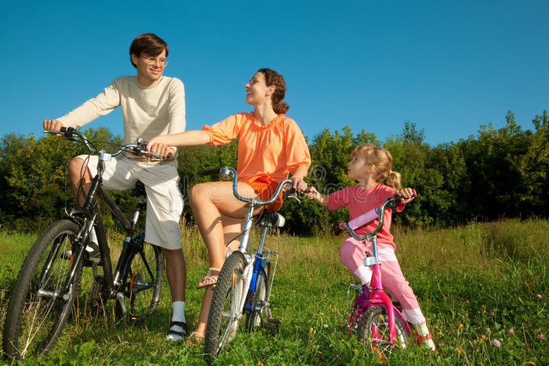 Father, mum and daughter on bicycles in park