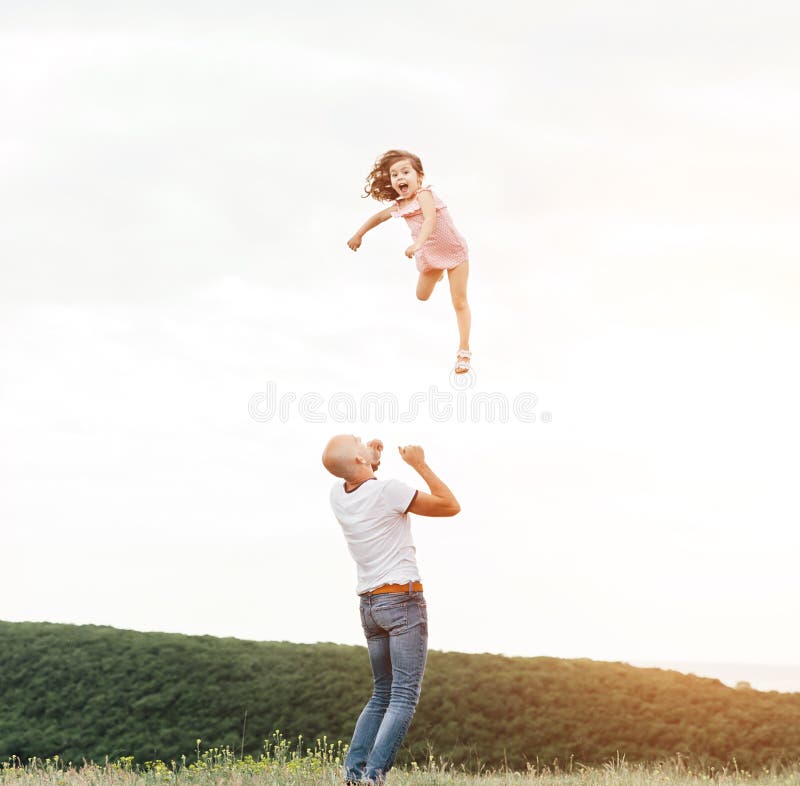 Father playing with his daughter in sunny field