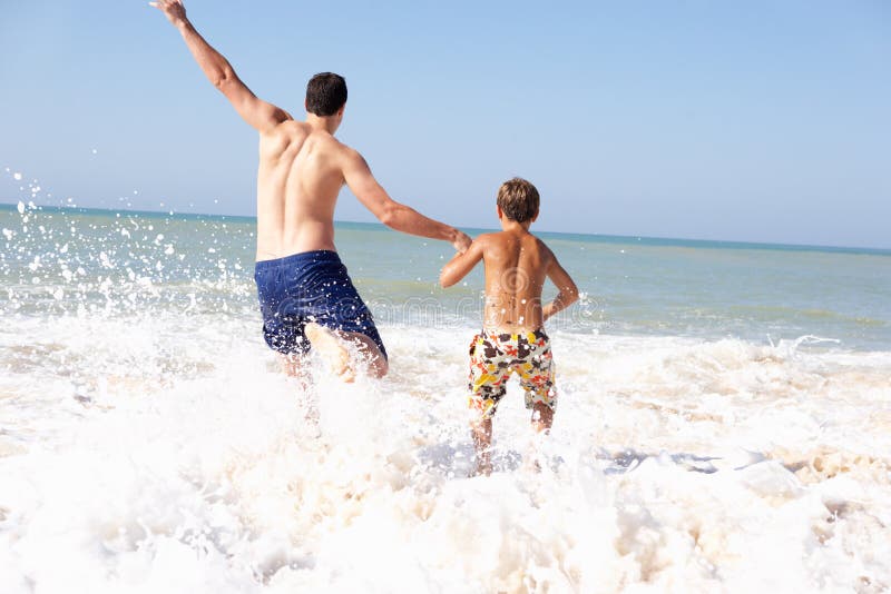 Father playing with young boy on beach