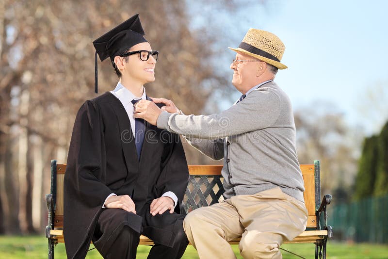 Father Preparing His Son For Graduation In Park Stock