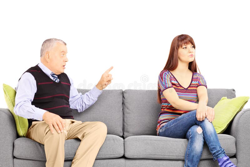 Father reprimending his uninterested daughter seated on a sofa