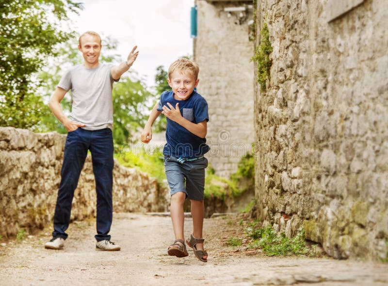 Father and running son on old street stock photos Father and running son on old street stock photos