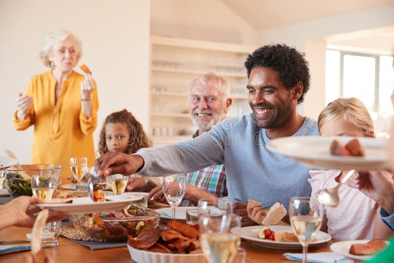 Father Serving Food As Multi-Generation Family Meet for Meal at Home ...