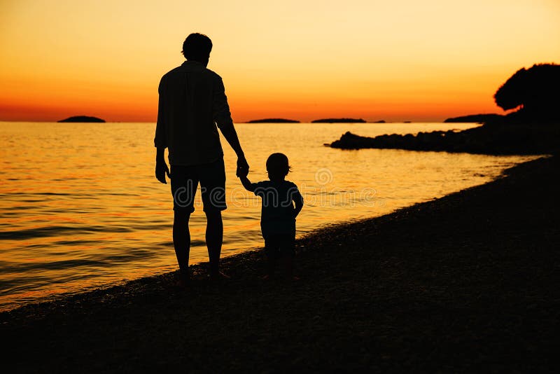 Father and son back silhouettes walking by the sea. royalty free stock images Father and son back silhouettes walking by the sea. royalty free stock images
