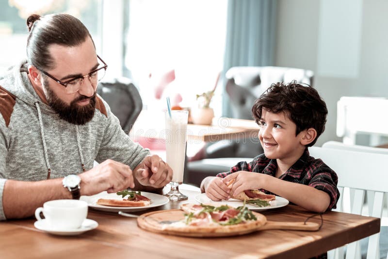 Father and son eating extremely yummy pizza with bacon and cheese stock images Father and son eating extremely yummy pizza with bacon and cheese stock images