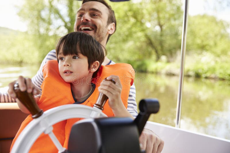 Father And Son Enjoying Day Out In Boat On River Together