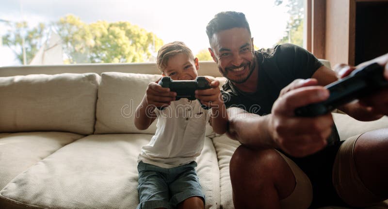 Father and Son Playing Video Games --- Image by © Royalty-…