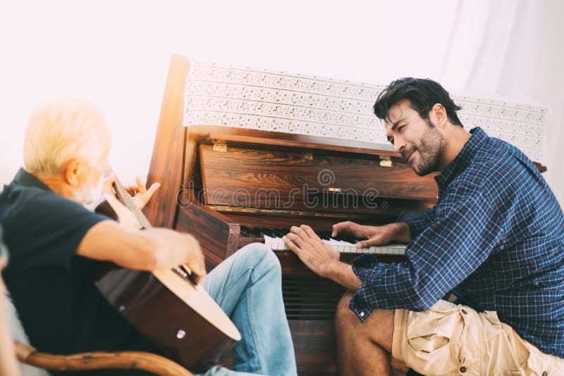 Father and son family time together at home concept. Happy old father and son playing guitar and piano at the Living room at home stock photography Father and son family time together at home concept. Happy old father and son playing guitar and piano at the Living room at home stock photography